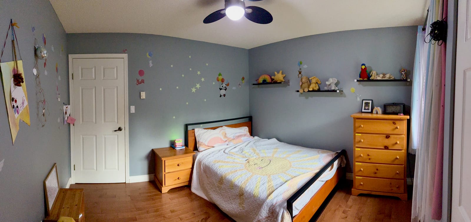 photo of the bedroom after reno - furniture, cute sunshine blanket, rainbow curtains.